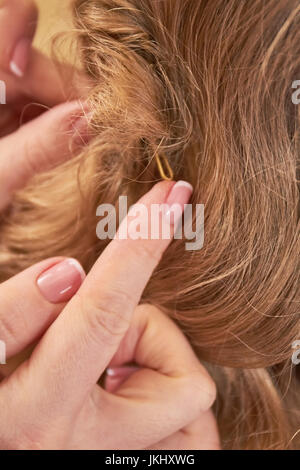 Mani femminili e capelli, macro. Foto Stock