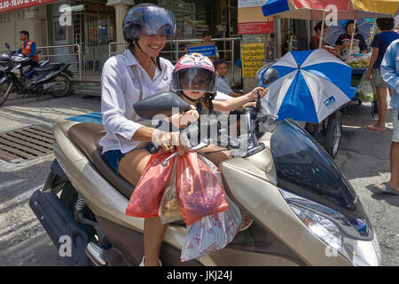 Motocicletta per bambini. Madre con bambino passeggero a bordo di una moto in Thailandia Sud-Est asiatico. Donna in moto Foto Stock