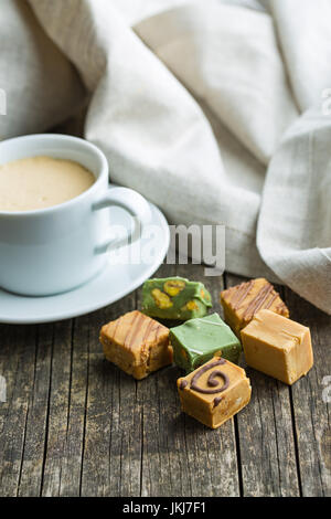 Colorate caramelle di caramello e la tazza di caffè sul tavolo. Foto Stock