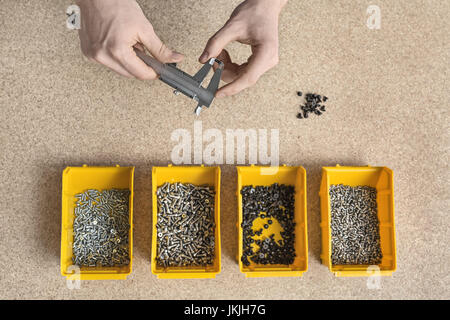 Scatole di plastica con le viti e le mani maschio Foto Stock