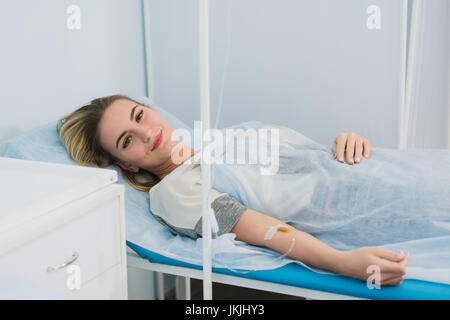 Donna sdraiata nel letto di ospedale e sorridente. Foto Stock