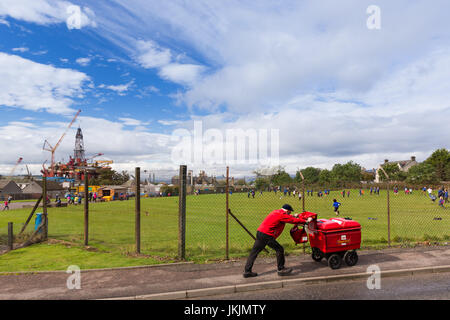 Invergordon, Scozia: portalettere / supporto per posta il passaggio di recinzione di scuola parco giochi. Piattaforma di perforazione in background. Foto Stock