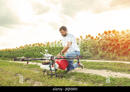 Giovane uomo riversa fertilizzante per l'irrigazione in agricoltura drone. Foto Stock