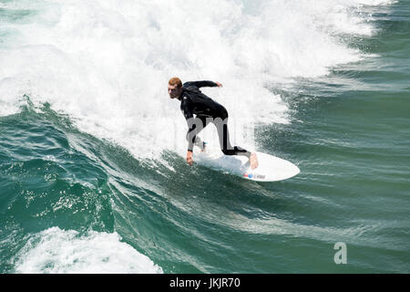 Un surfista cattura le onde a Manhattan Beach, CA, Stati Uniti d'America Foto Stock