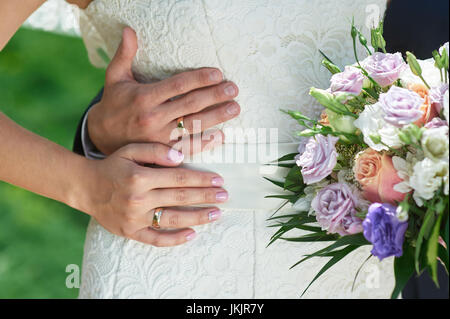 Lo sposo abbraccia le spose in vita su un matrimonio a piedi. Foto Stock