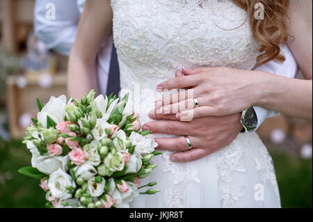 Lo sposo abbraccia le spose in vita su un matrimonio a piedi. Foto Stock