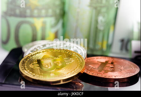 Bitcoin monete sullo smartphone su banconote denaro sfondo Foto Stock