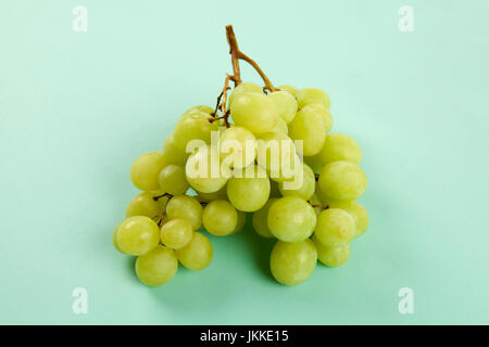 Design Minimal still life fotografia. grappolo di uva in una vibrante colore di sfondo viola e turchese Foto Stock