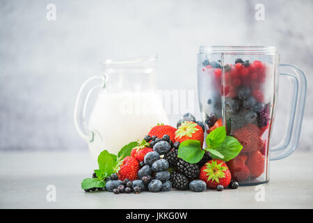 Frullatore con frutta e vaso di latte per frullato. Foto Stock