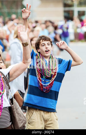 Ragazzo con le braccia fino a un massimo di catture Mardi Gras perline. Foto Stock