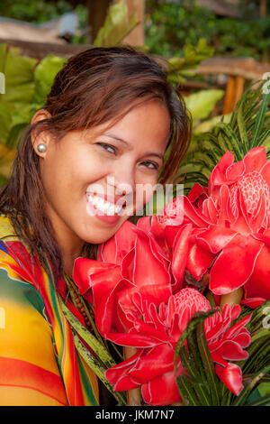 Ritratto di una bella donna filippina con un meraviglioso sorriso tenendo un mazzo di Filippino rosso fiori di cera, Etlingera elatior. Modello rilasciato. Foto Stock