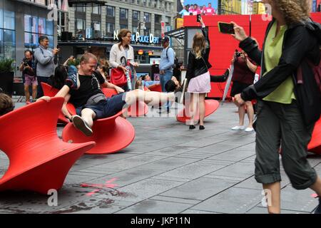 New York, US. Il 24 luglio, 2017. New York, NY, USA. -- 24 luglio, 2017-- i giovani e i giovani di cuore i visitatori a Times Square si fermò un momento di divertimento a mezzogiorno con il Magis Spun sedia. Il montante filate sedie è un affascinante sedia che assomiglia più ad un recipiente scultoreo di un sedile. Ma quando si appoggia sul suo lato, si forma una confortevole sedia funzionale che consente di roccia da lato a lato o girare intorno a. Credito: G. Ronald Lopez /DigiPixsAgain.us/Alamy Live News Foto Stock