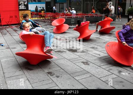 New York, US. Il 24 luglio, 2017. New York, NY, USA. -- 24 luglio, 2017-- i giovani e i giovani di cuore i visitatori a Times Square si fermò un momento di divertimento a mezzogiorno con il Magis Spun sedia. Il montante filate sedie è un affascinante sedia che assomiglia più ad un recipiente scultoreo di un sedile. Ma quando si appoggia sul suo lato, si forma una confortevole sedia funzionale che consente di roccia da lato a lato o girare intorno a. Credito: G. Ronald Lopez /DigiPixsAgain.us/Alamy Live News Foto Stock