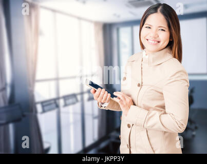 Donna asiatica indossando cappotto marrone e azienda tablet Foto Stock