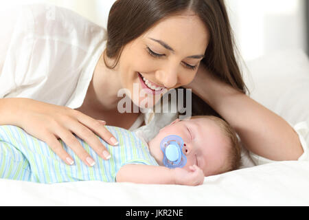 Mamma orgogliosa guardando il suo bambino di dormire su un letto di casa Foto Stock