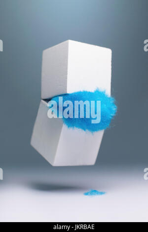 Pelliccia blu di cadere fuori dalla scatola bianca contro lo sfondo grigio Foto Stock