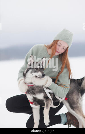 Bella giovane donna stroking Siberian Husky sul campo nevoso Foto Stock