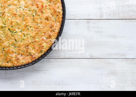 Crostata di zucchine in padella nero su bianco tavola di legno, vista dall'alto Foto Stock