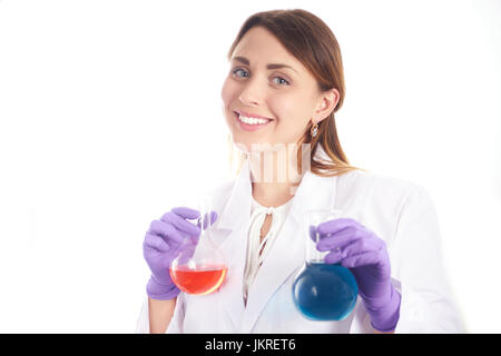 Giovane donna sorridente in panno scientifici tenendo beute con liquidi colorati. isolato su bianco. Foto Stock