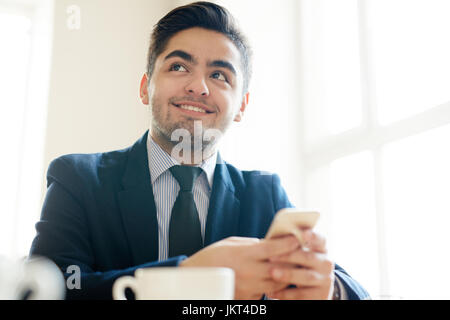 Agente di giovani in tuta tenendo lo smartphone nel mani Foto Stock