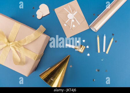 Vista superiore della confezione regalo, candele, compleanno hat ed involucro isolato sul blu, festa di compleanno di concetto Foto Stock