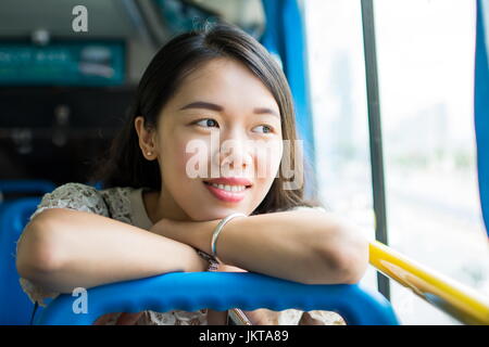 Allegro ragazza asiatica seduti su un autobus pubblico Foto Stock