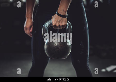 Donna dentro una palestra che lavora fuori con un kettlebell. Foto Stock