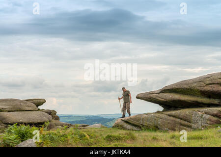 Uomo che cammina su Owler Tor, Peak District, REGNO UNITO Foto Stock