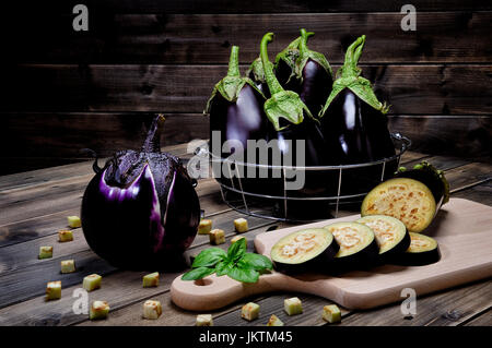 Close up di fresca tutta viola melanzane a fette e su un vecchio tavolo di legno. Foto Stock