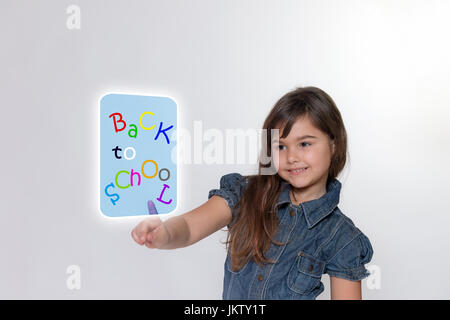 Capelli lunghi sorridente bambina è di toccare con il suo dito indice un rettangolo trasparente wth iscrizione torna a scuola . Tutto è in grigio chiaro backgr Foto Stock