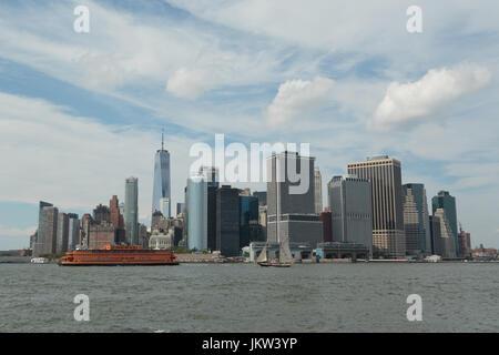 Una fotografia della skyline di Manhattan, come si vede dal Governor's Island, New York City. L'iconico orange Staten Island Ferry e una vecchia nave a vela can b Foto Stock