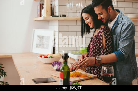 Amorevole coppia giovane tagliare le verdure insieme al banco di cucina. Giovane uomo e donna la cottura di cibo insieme a casa. Foto Stock