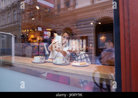 Giovane madre e figlia di trascorrere del tempo in cafe e rendendo le foto Foto Stock