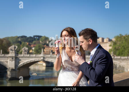 Sposa e lo sposo wedding pone con gelato in Vaticano sulla banca del fiume Tevere a Roma, Italia Foto Stock