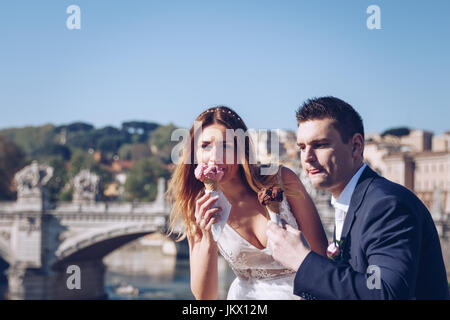 Sposa e lo sposo wedding pone con gelato in Vaticano sulla banca del fiume Tevere a Roma, Italia Foto Stock