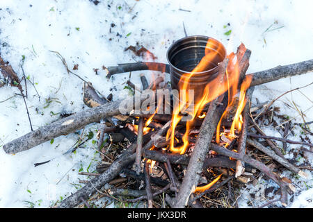 La sopravvivenza in inverno - acqua bollente per il tè su piccoli falò Foto Stock