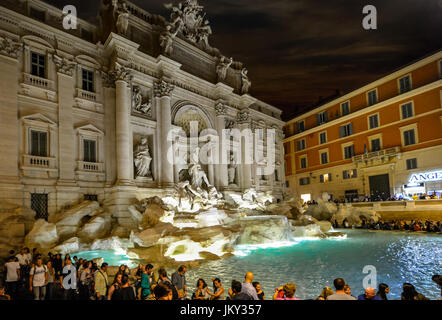 Calda notte d'estate a Roma Italia come la folla di turisti godere la Fontana di Trevi e la vita notturna in una trafficata piazza Foto Stock