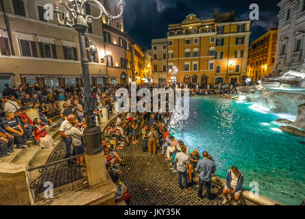 Una grande folla di turisti godere la Fontana di Trevi in una calda serata estiva in Roma Italia Foto Stock
