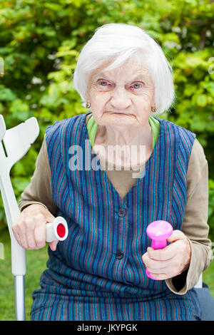 Foto di eccitato donna anziana facendo sport esercizi all'aperto nel giardino, azienda rosa manubri Foto Stock