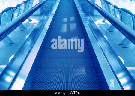 Concetto di viaggio. Escalator cammino interno moderno aeroporto terminale. Immagine in colori blu Foto Stock