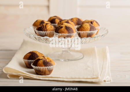 Muffin su una targhetta sulla luce sullo sfondo di legno. Messa a fuoco selettiva. Foto Stock