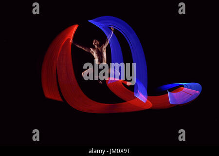 Attraente uomo ballet dancing con luci incandescenti effetto su sfondo nero Foto Stock