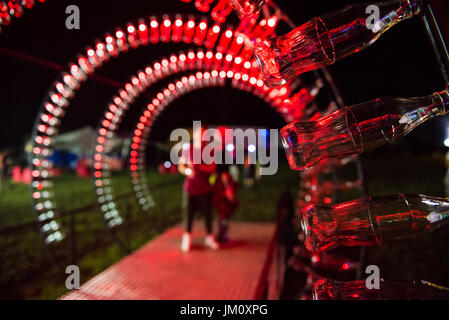 BONTIDA, Romania - 13 luglio 2017: Vuoto Coca Cola bottiglie sono disposte in una forma di tunnel e illuminato con luci rosse al castello elettrico festi Foto Stock