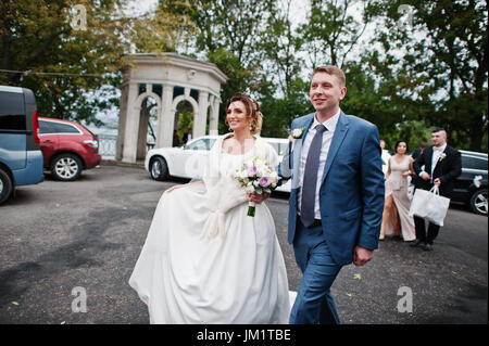 Coppie in viaggio di nozze a piedi nelle strade della città con groomsmen e damigelle. Foto Stock