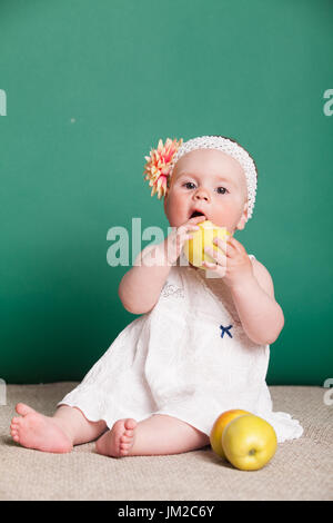 Baby ragazza in un abito con mele verdi Foto Stock