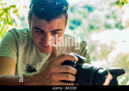 Ragazzo di scattare una foto con una fotocamera fissata su un treppiede Foto Stock