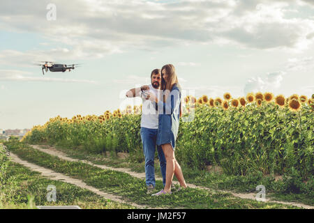 Giovane uomo operante di flying drone octocopter in corrispondenza del campo verde. Foto Stock