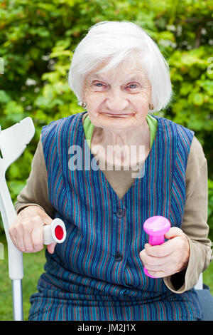 Foto di eccitato donna anziana facendo sport esercizi all'aperto nel giardino, azienda rosa manubri Foto Stock