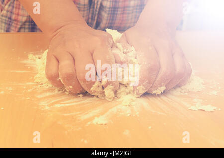 Una donna massaggia una pasta fatta in casa per la produzione di pizze Foto Stock