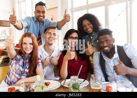 Happy amici mostrando i pollici fino al ristorante Foto Stock